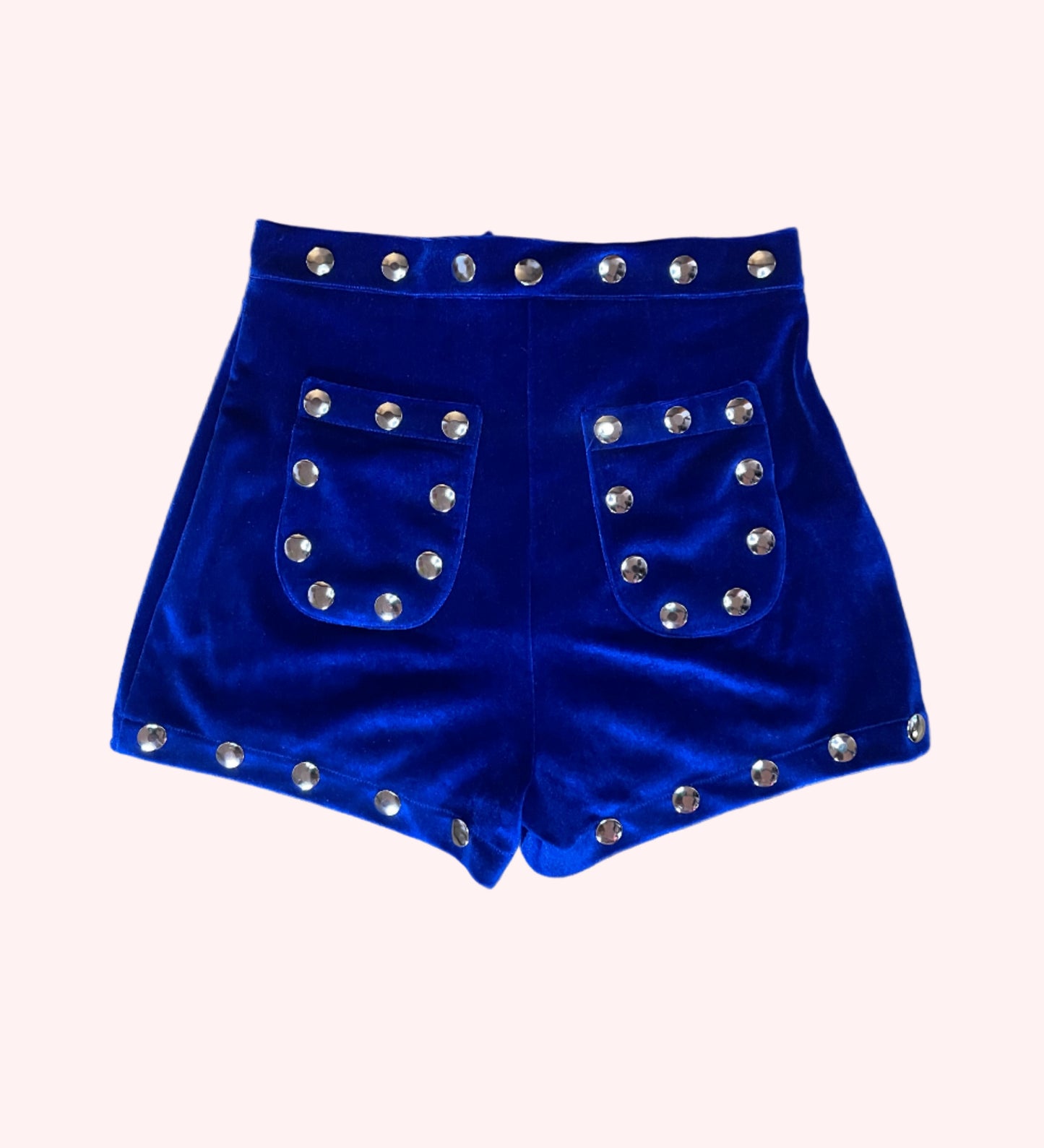 Blue velvet shorts with silver studs on a wooden surface