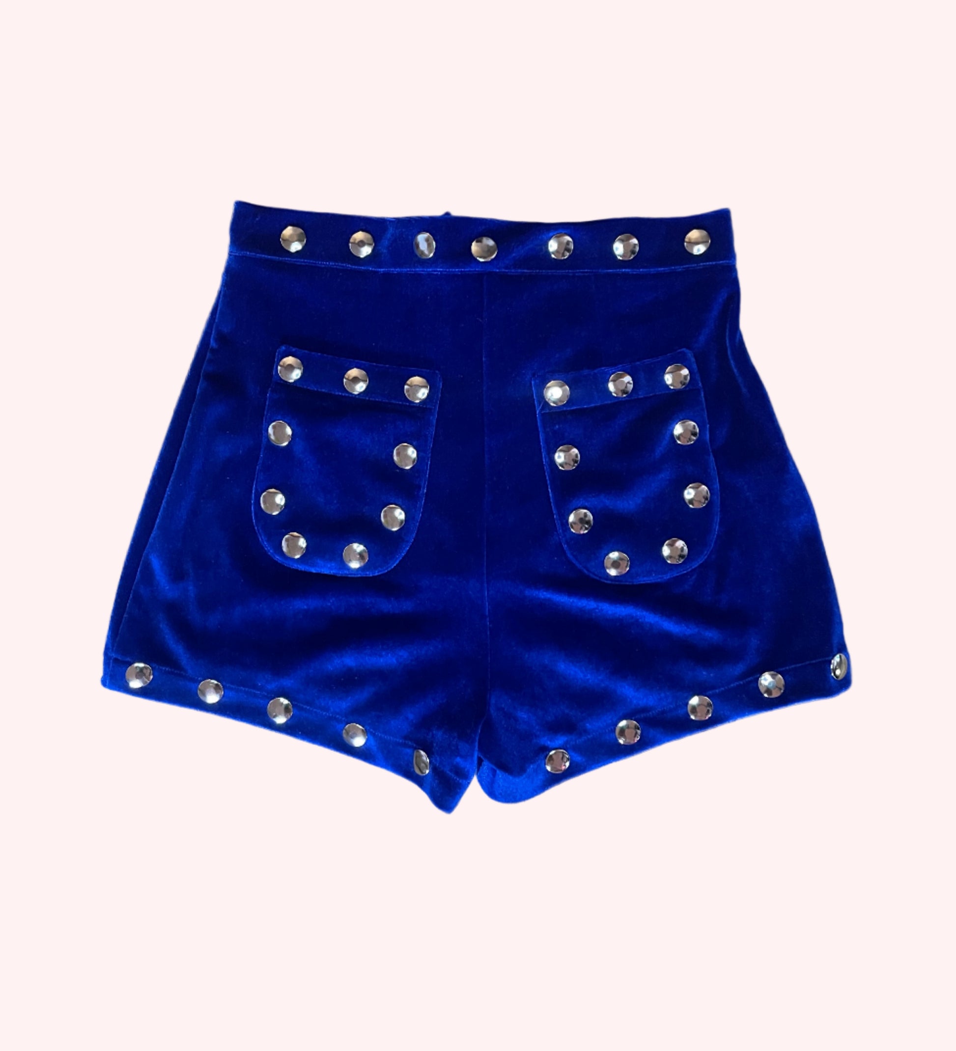 Blue velvet shorts with silver studs on a wooden surface